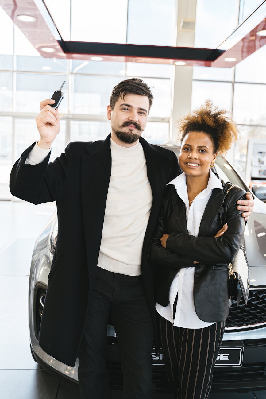 a couple standing in front of a brand new car